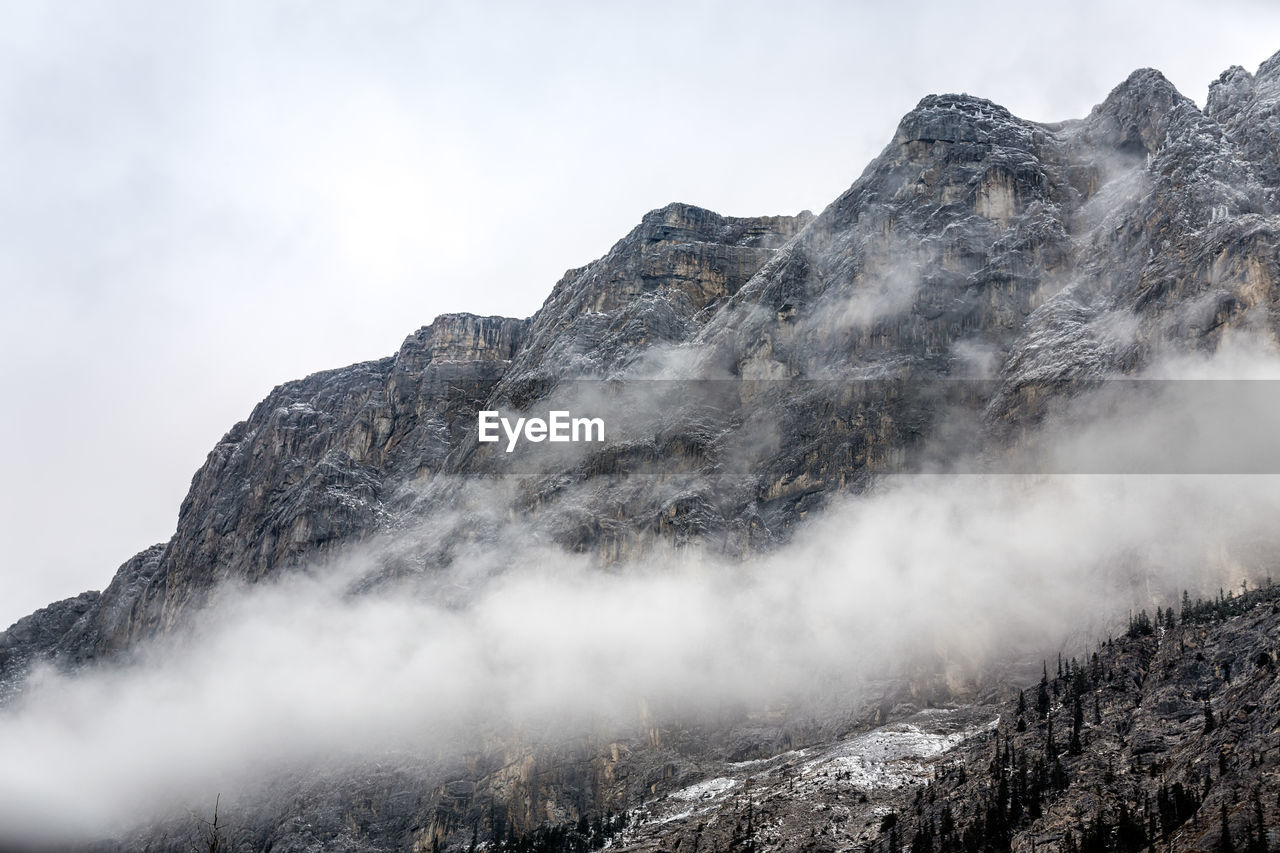 Smoke emitting from mountain against sky