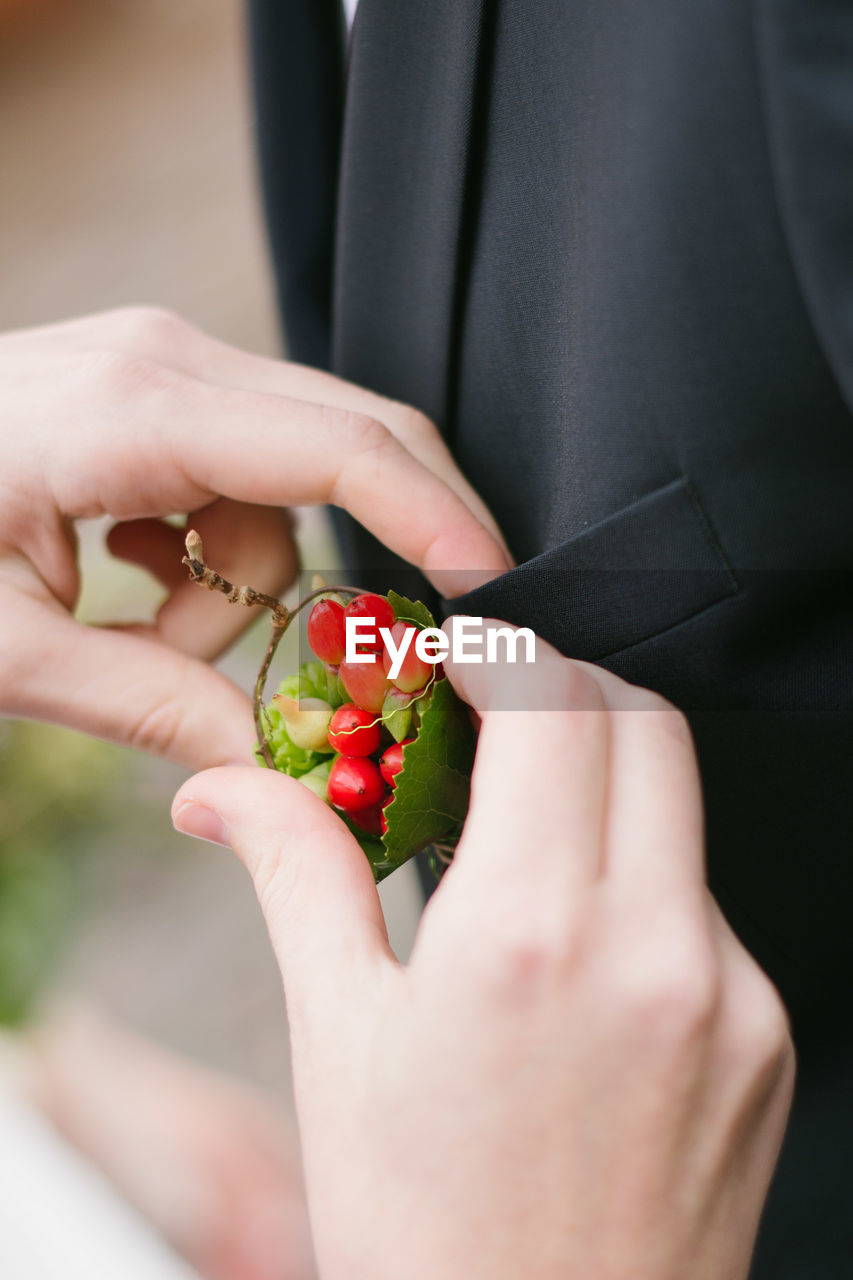 Cropped hand adjusting brooch on man suit