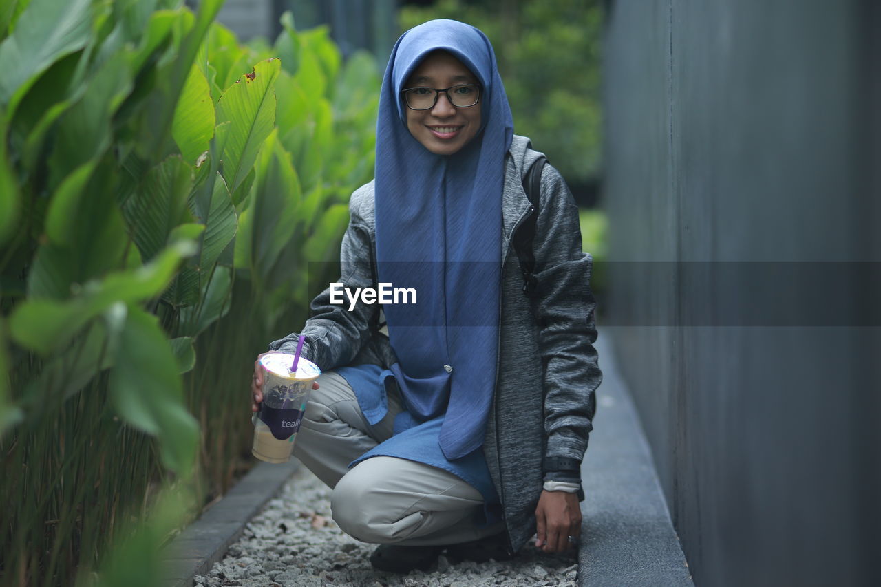 YOUNG WOMAN WEARING SUNGLASSES WITH PLANTS