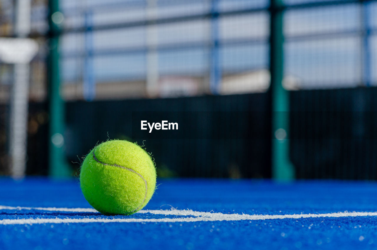 tennis ball, tennis, sports, ball, green, tennis racket, tennis net, racket, net - sports equipment, competition, no people, sports equipment, focus on foreground, selective focus, day, activity, sphere, tennis court, blue, close-up, outdoors, leisure activity, motion