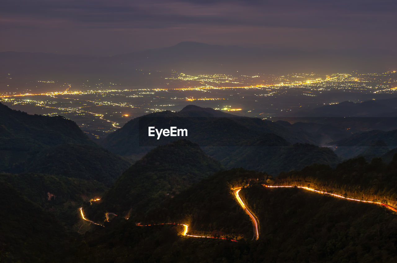 Aerial view of illuminated road on mountain against sky at night