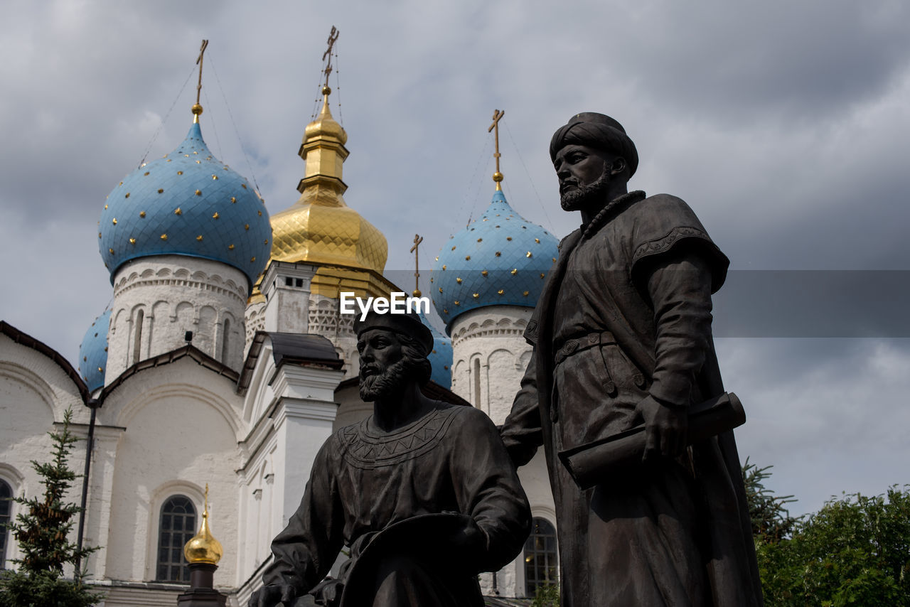 Statues and russian orthodox church against cloudy sky