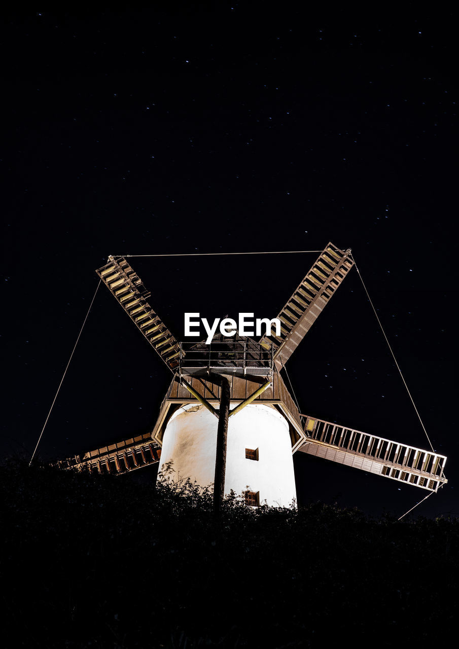 LOW ANGLE VIEW OF ILLUMINATED BUILDING AGAINST SKY AT NIGHT