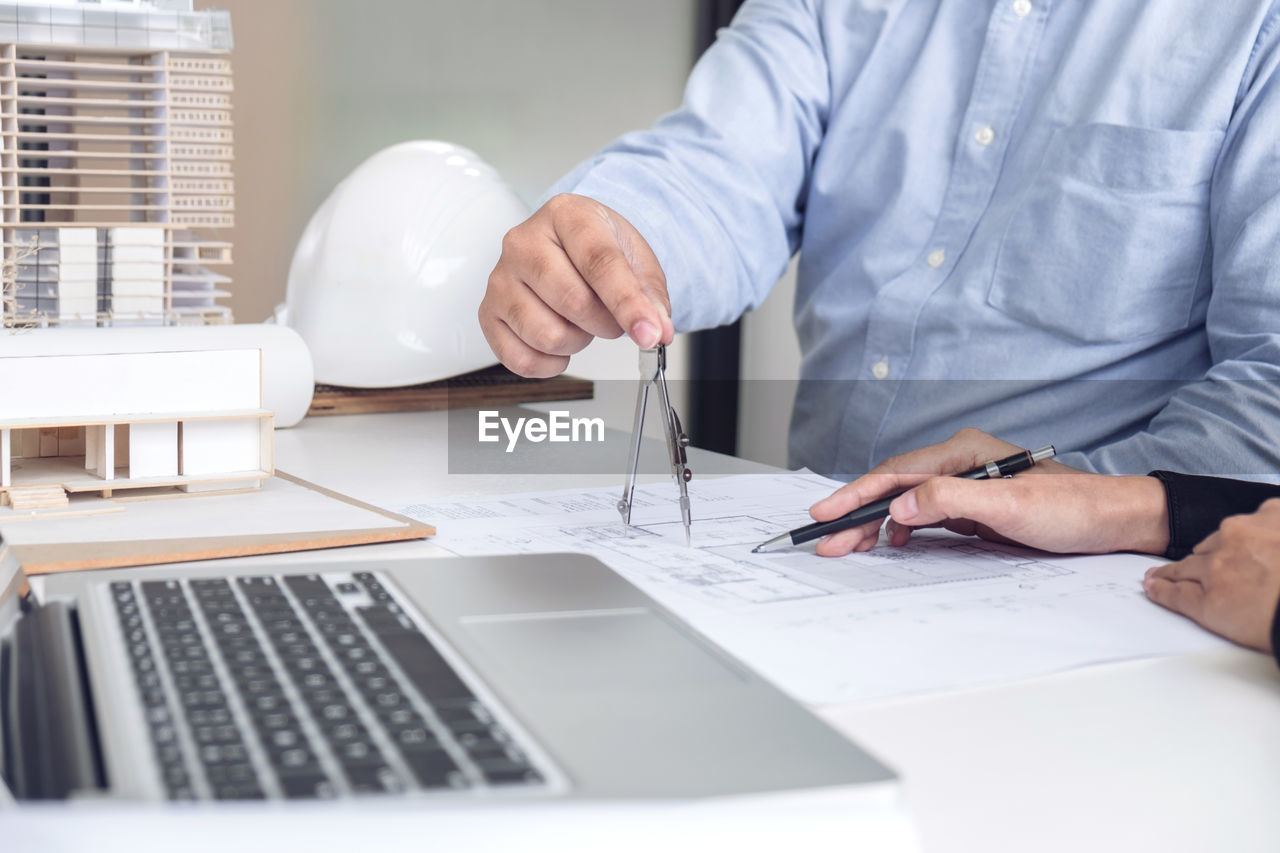 Midsection of business people working at desk in office