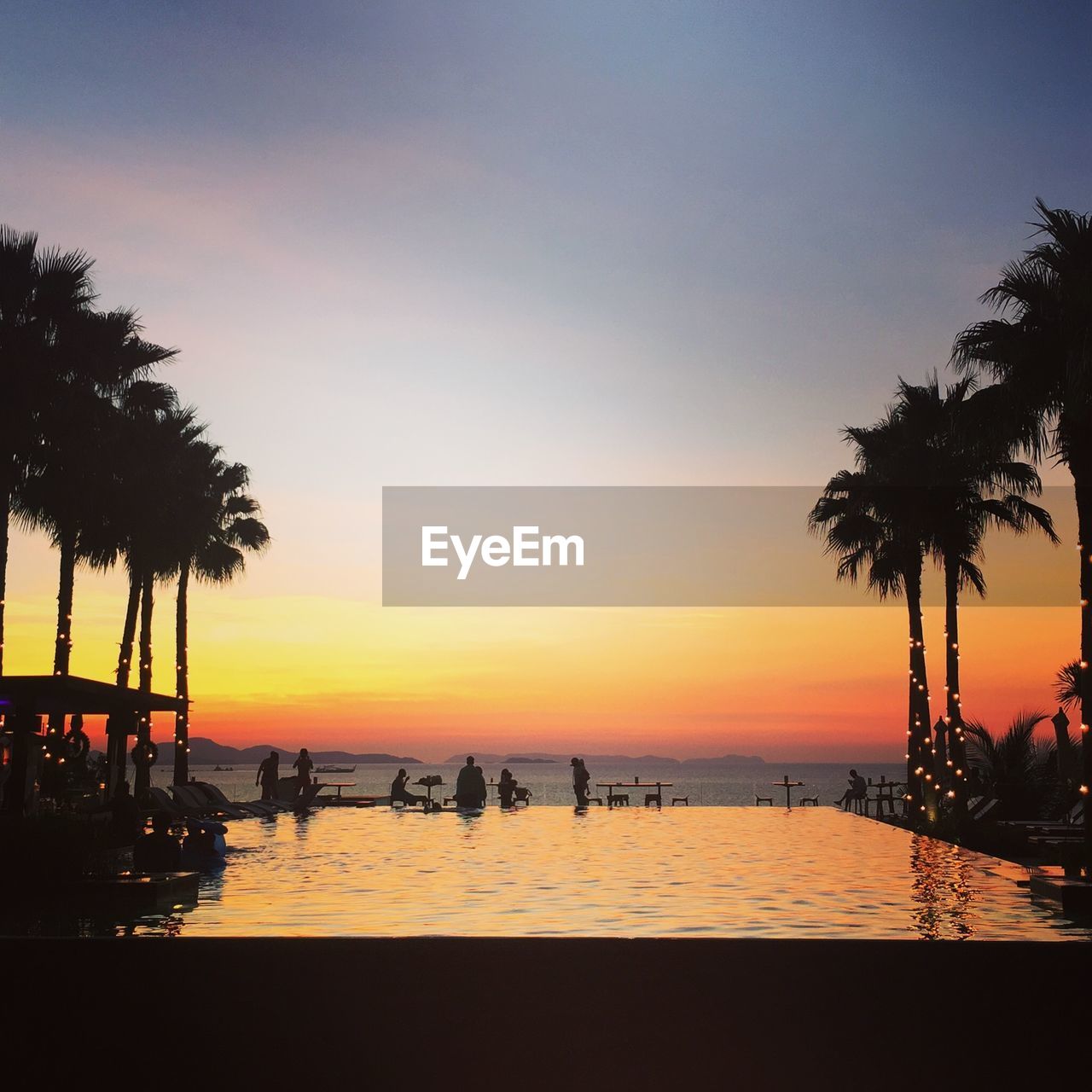 Infinity pool by sea against sky during sunset