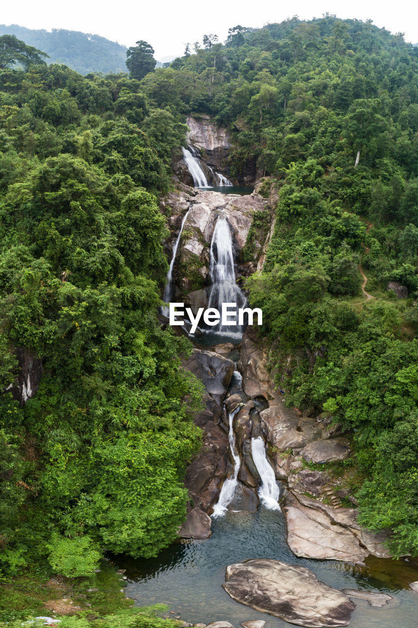 Scenic view of waterfall against rock formation in forest