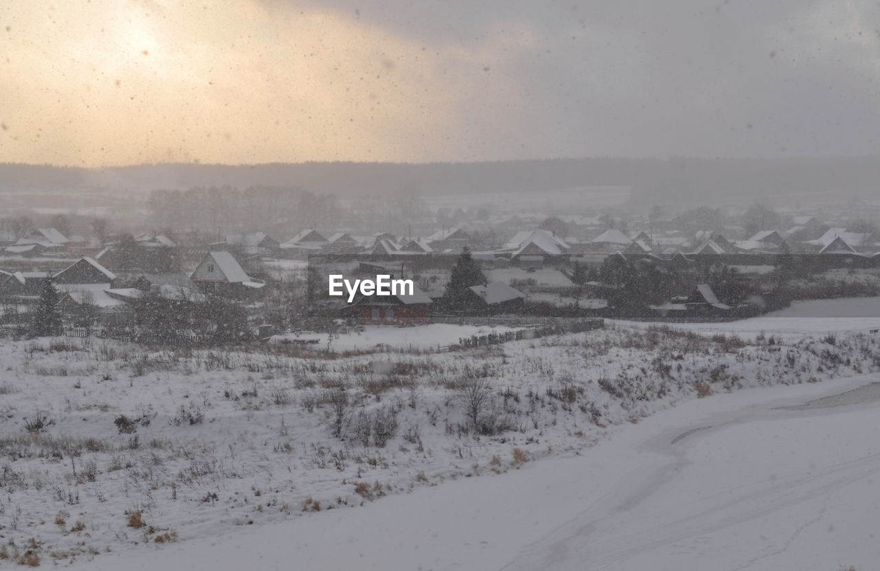 SNOW COVERED LANDSCAPE AGAINST BUILDINGS