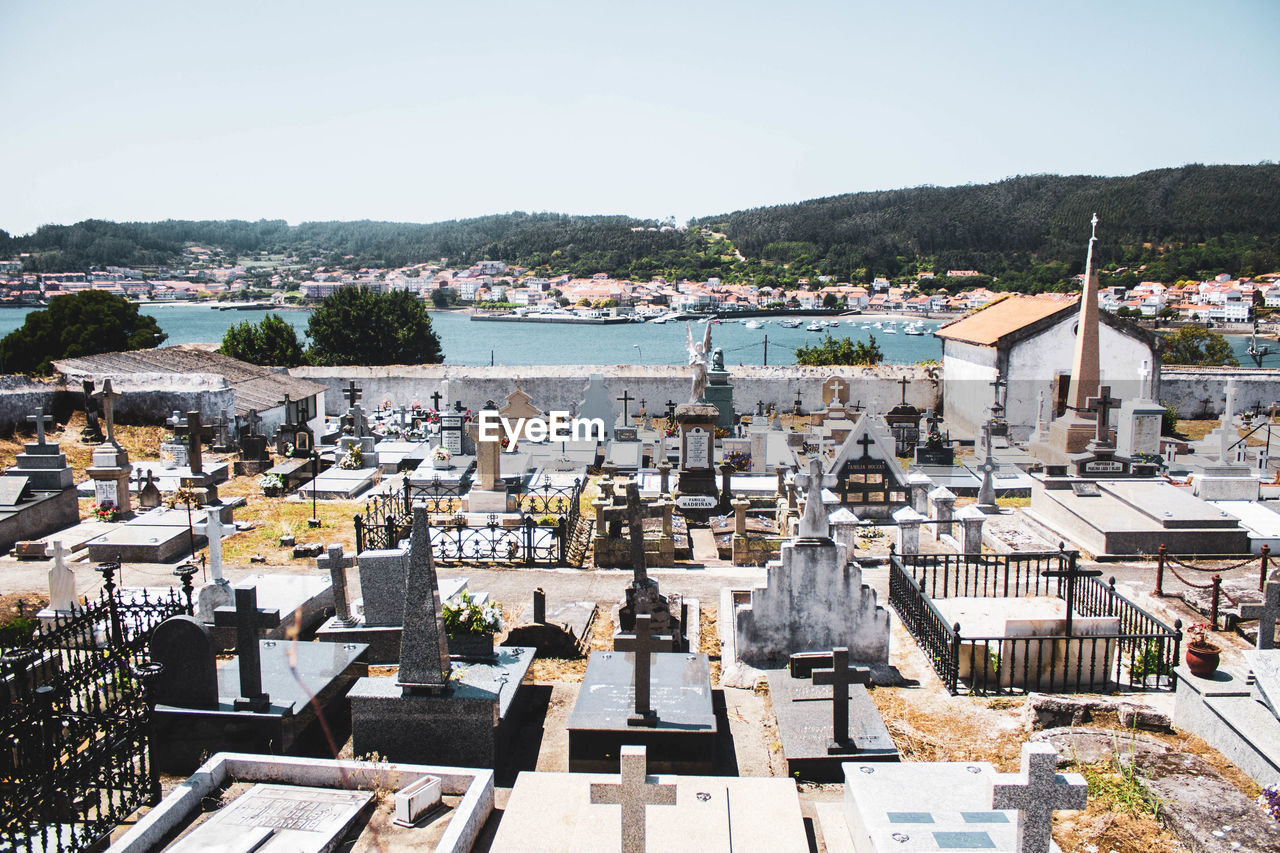 White graveyard by the sea against houses and mountains