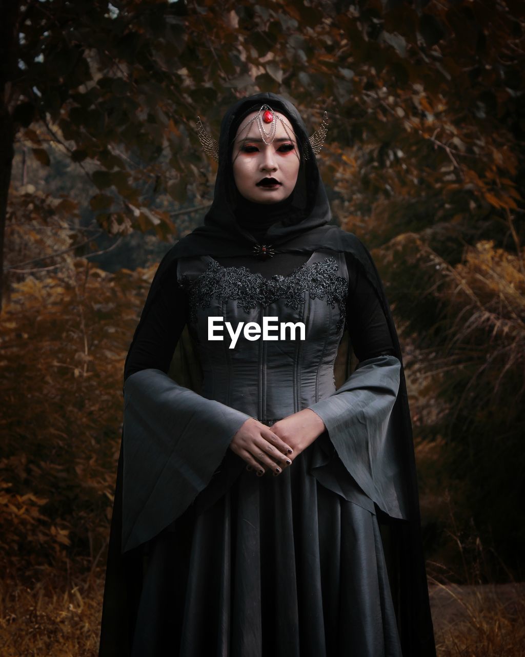 Portrait of young woman in halloween costume standing at forest during autumn