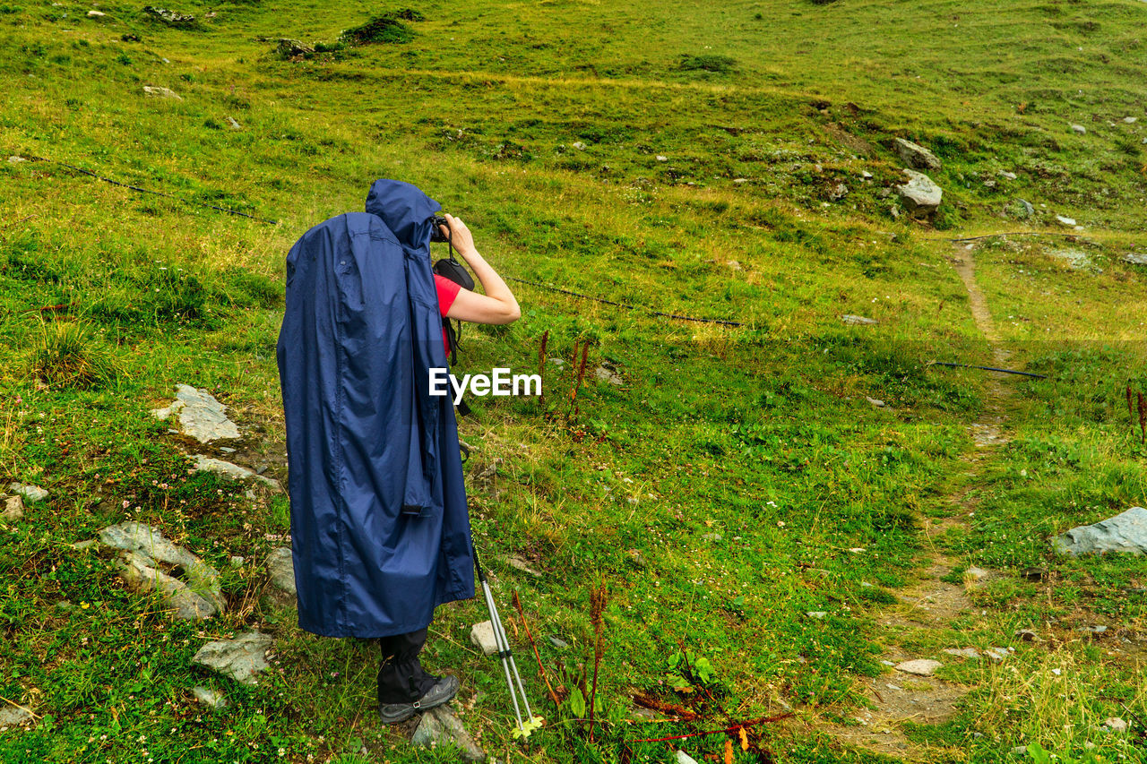 Side view of woman looking through binoculars while standing on land