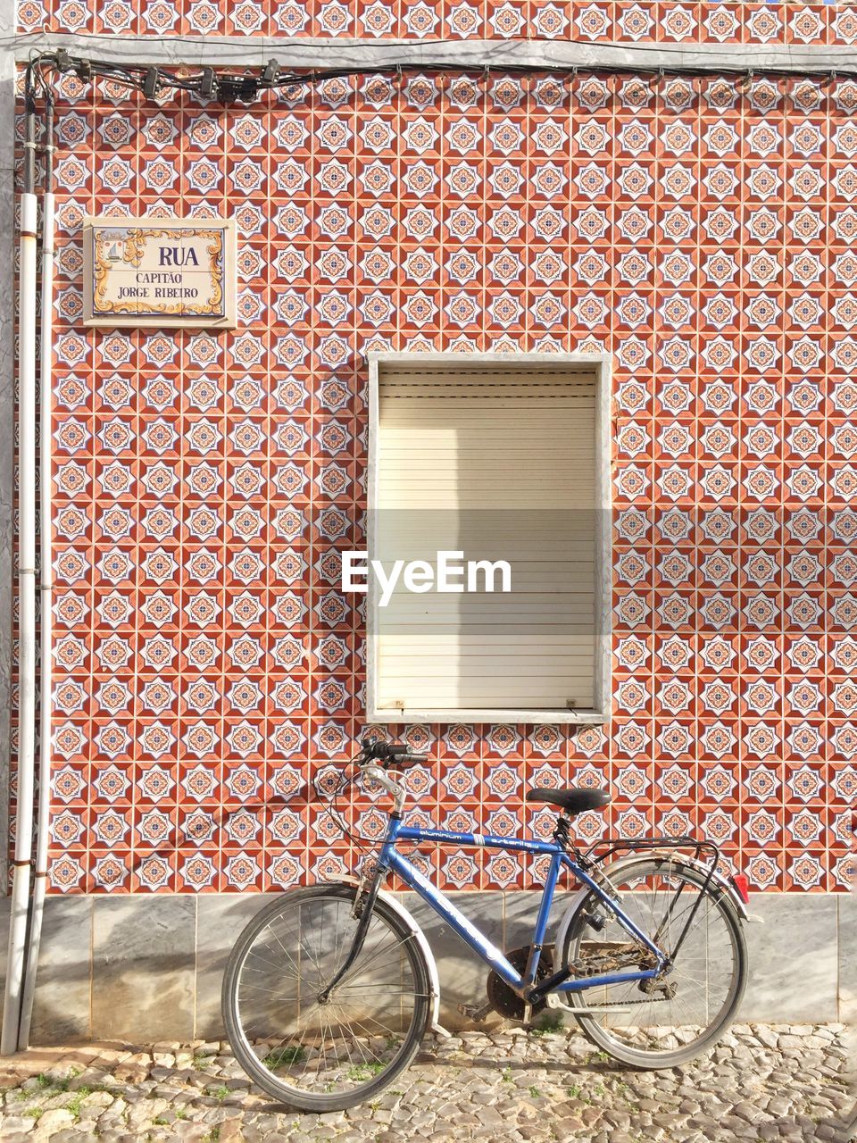 BICYCLE AGAINST BRICK WALL OF HOUSE