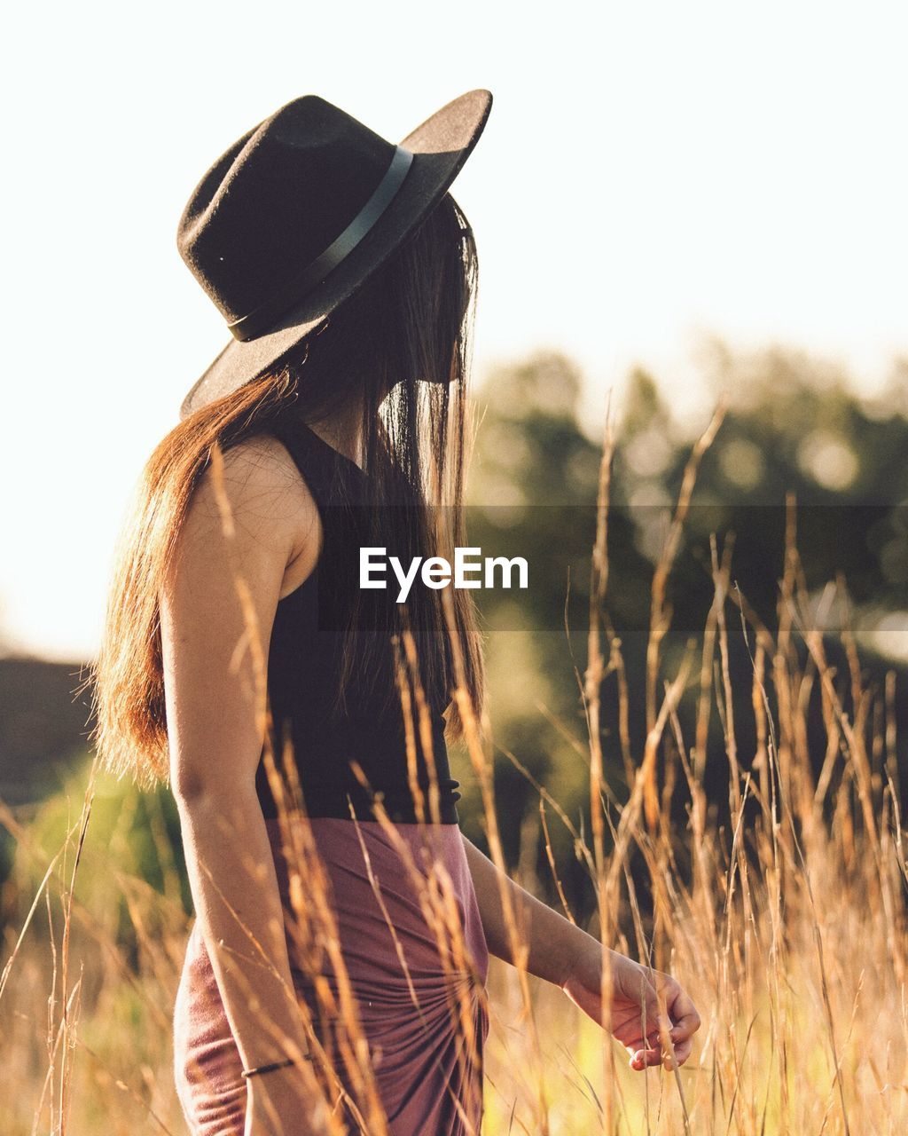 REAR VIEW OF WOMAN STANDING ON FIELD