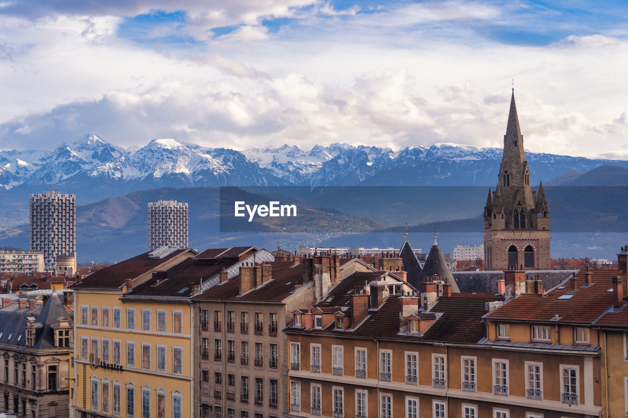 Buildings in city against cloudy sky