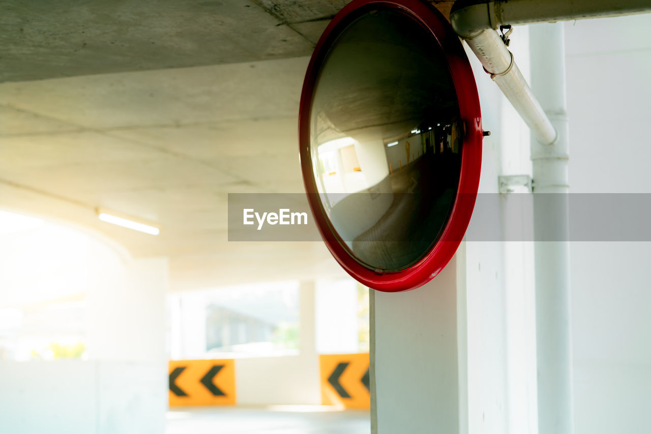 Convex safety mirror at curve of indoor car parking lot to reduce risk of accidents from blind 