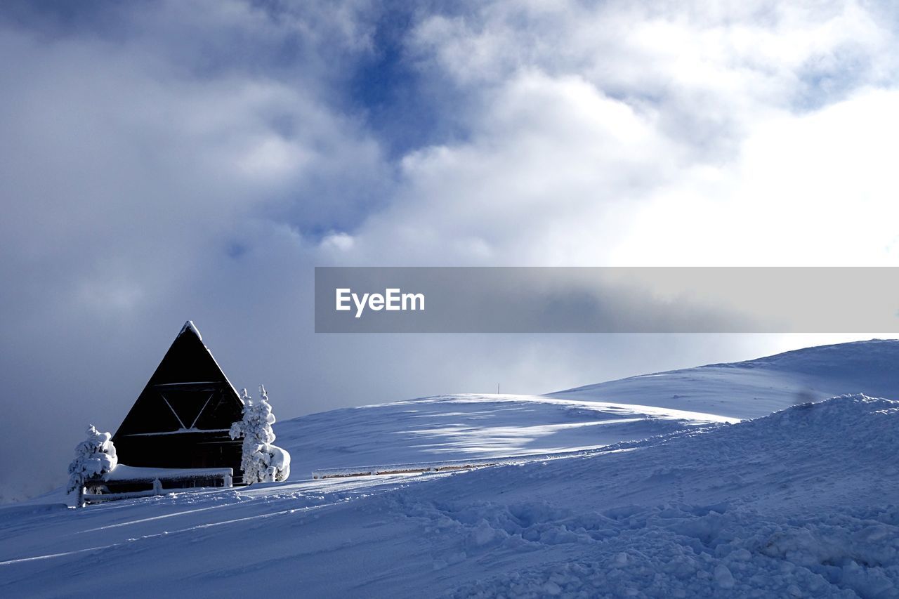 Built structure on snow covered landscape against sky