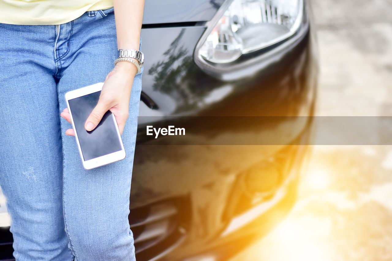 Midsection of woman standing by car