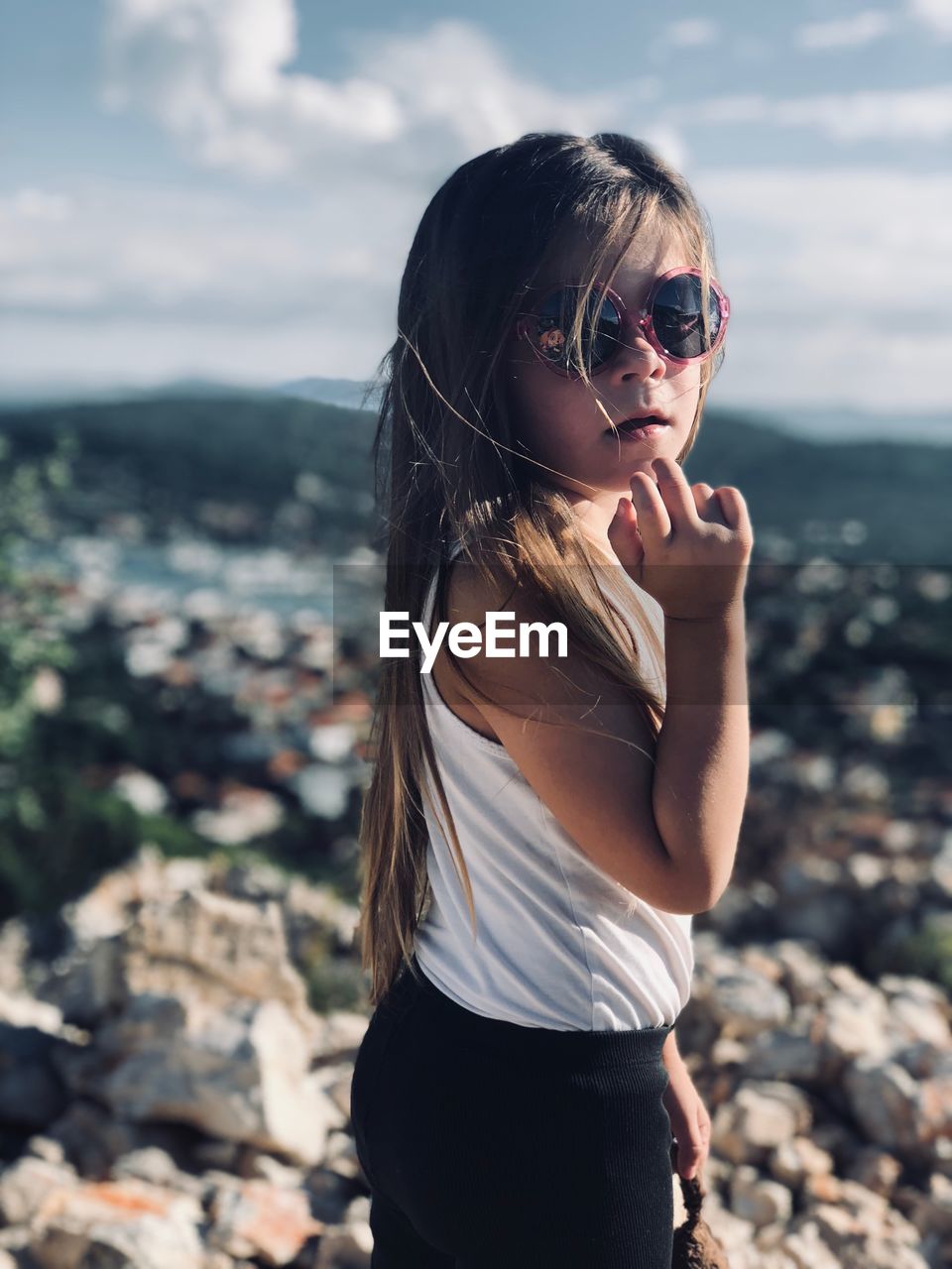 Girl wearing sunglasses standing against sky