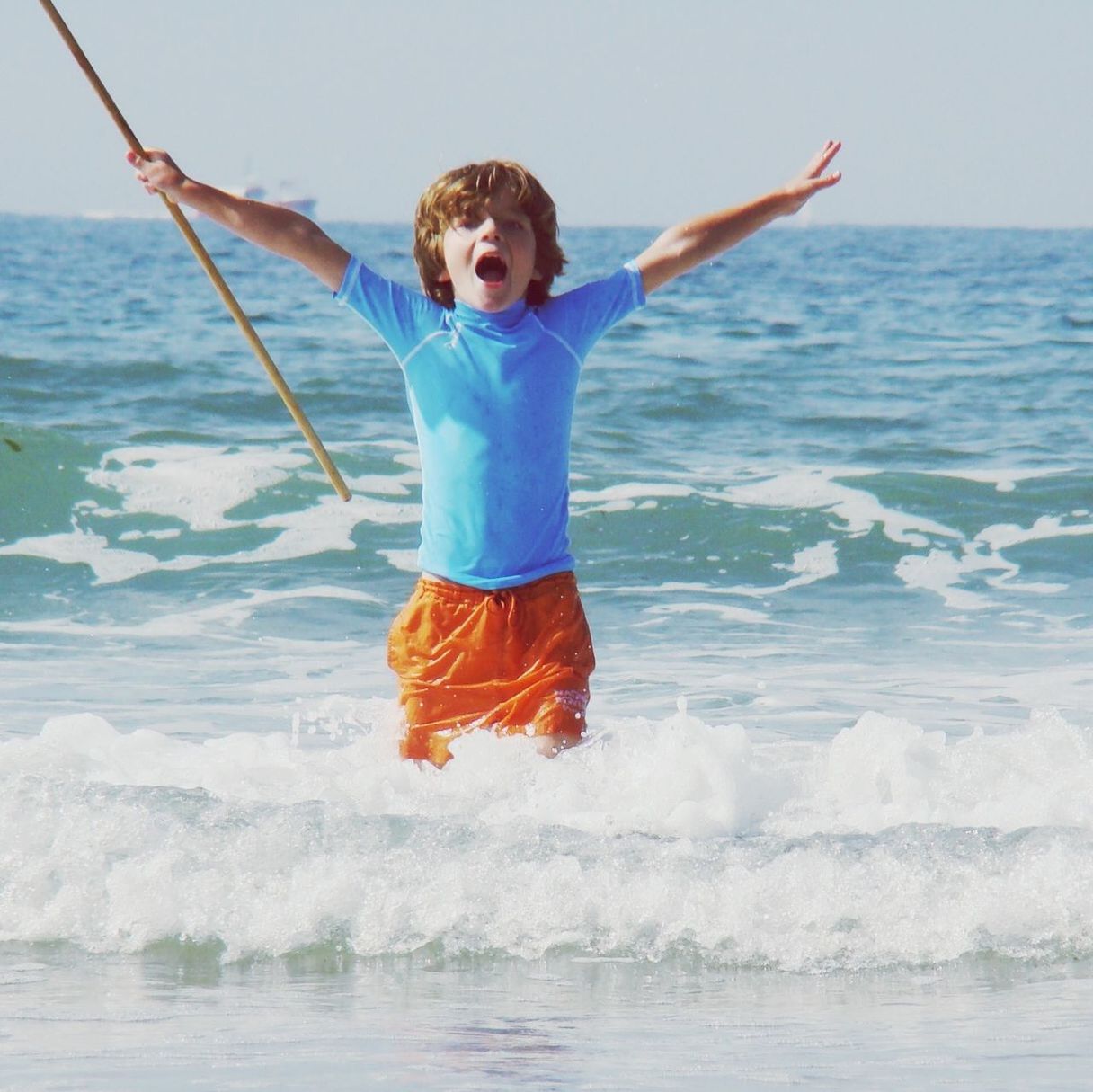 BOY JUMPING ON BEACH AGAINST SKY