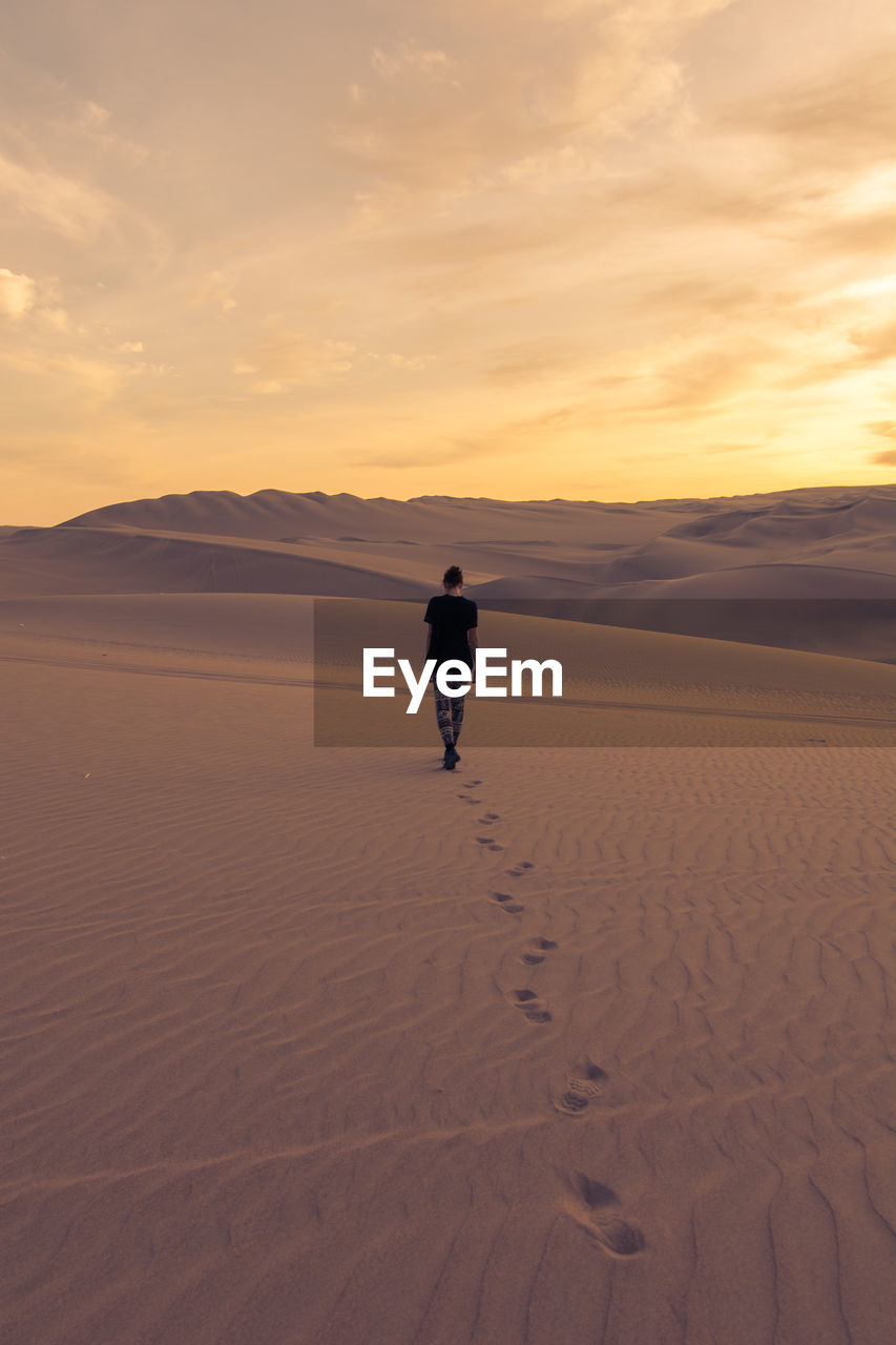 Rear view of woman walking in desert