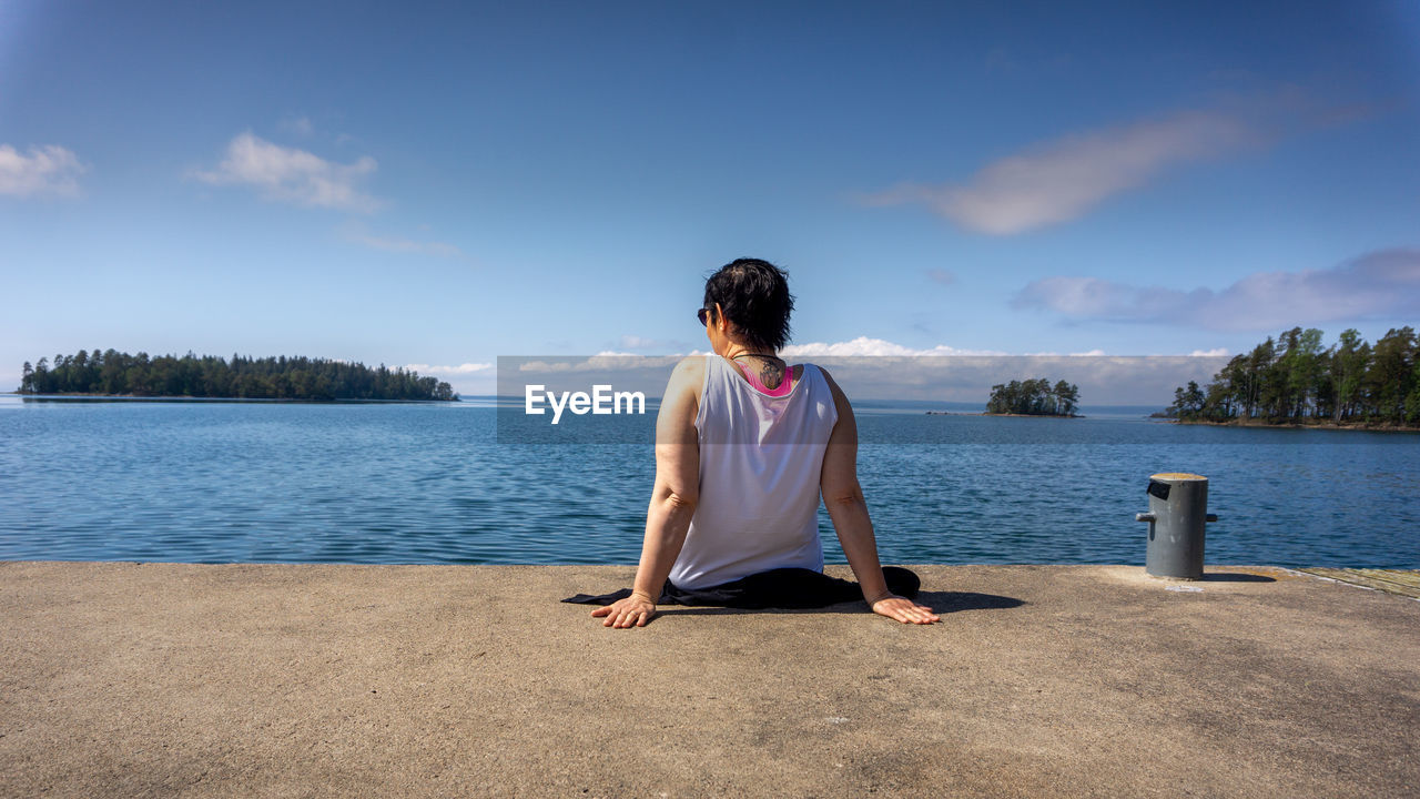 REAR VIEW OF WOMAN LOOKING AT SEA AGAINST SKY