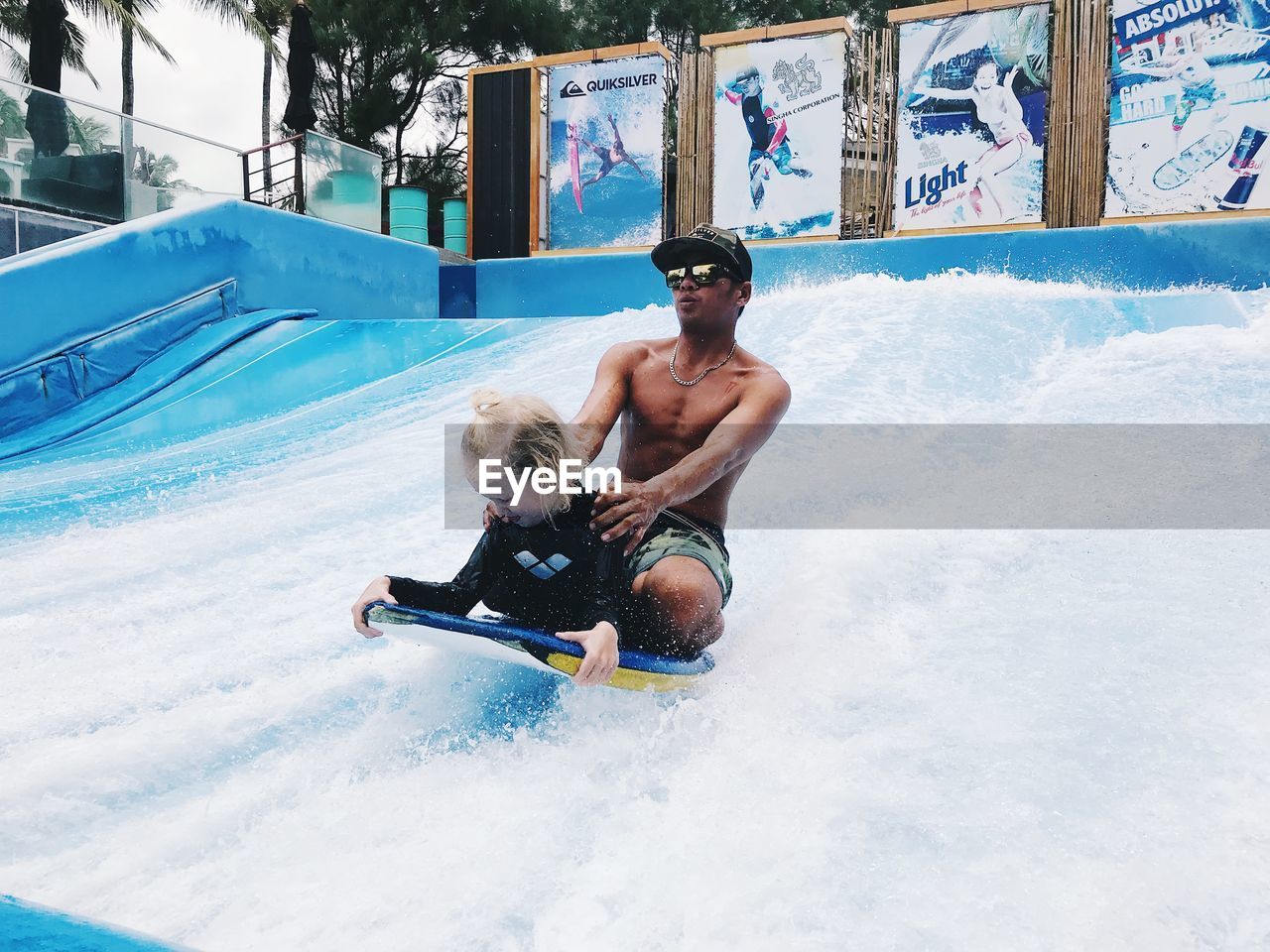 FULL LENGTH OF SHIRTLESS MAN IN WATER WHILE HOLDING UMBRELLA