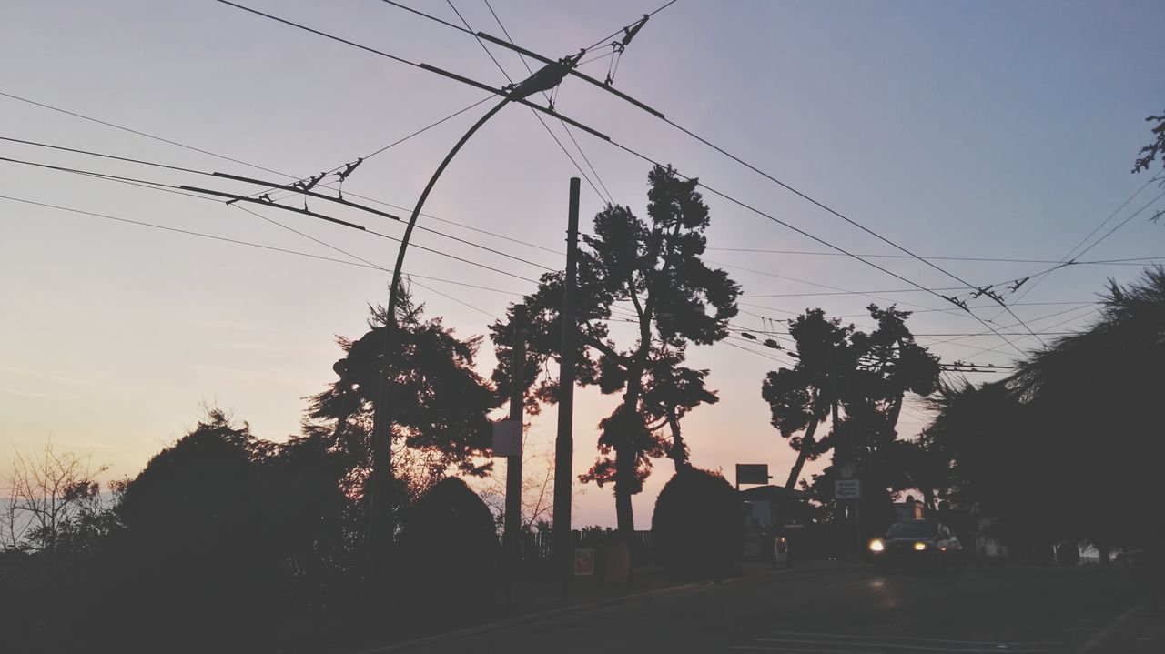 SILHOUETTE OF TREES AND ELECTRICITY PYLON AGAINST SKY