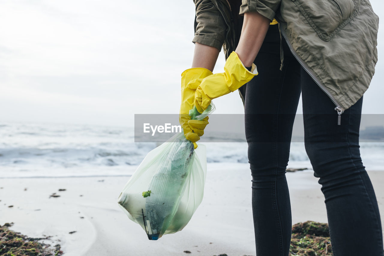 Woman collecting plastic waste at beach