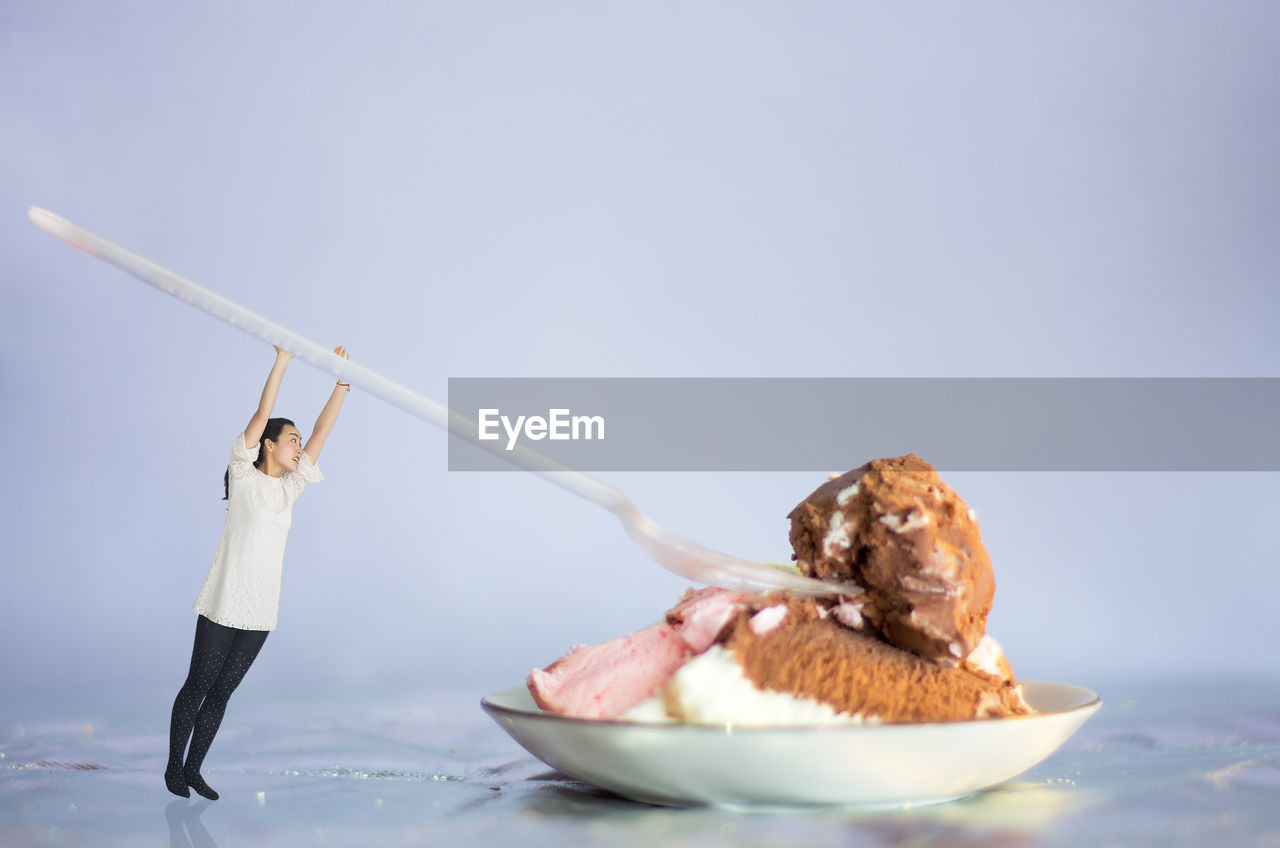 Digital composite image of woman having dessert against gray background