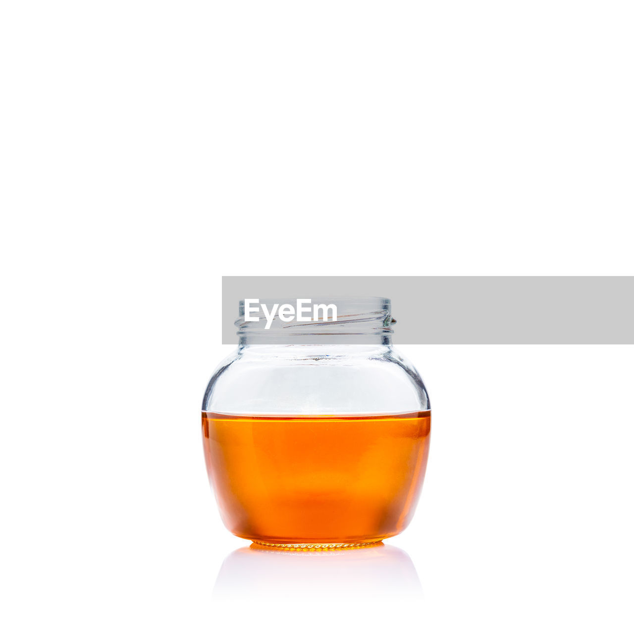 Honey in open lid glass jar on white background