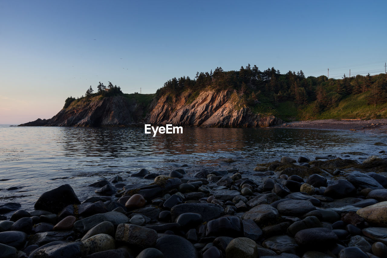 Rocks in sea against clear sky