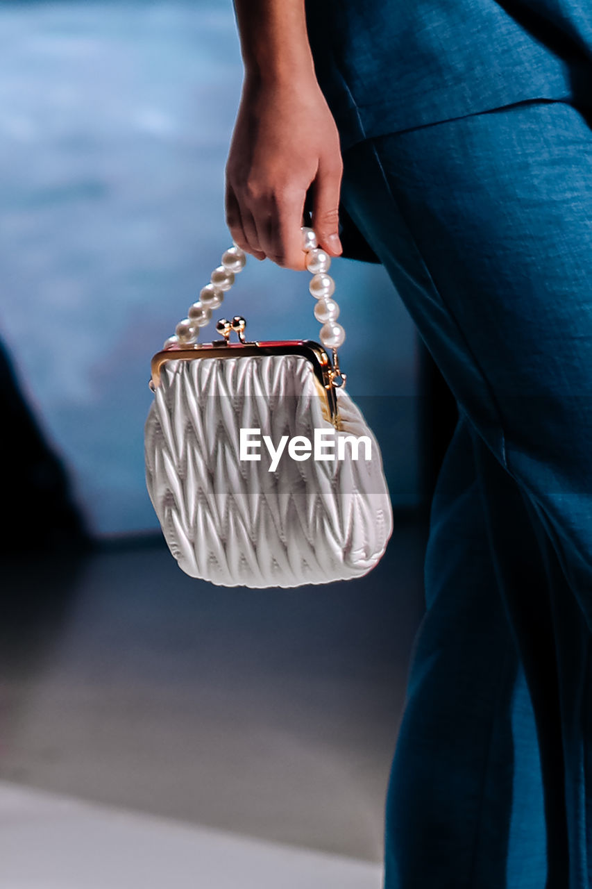 Fashionable details of a white clutch with beads in a woman's hand. elegant clothing and accessories