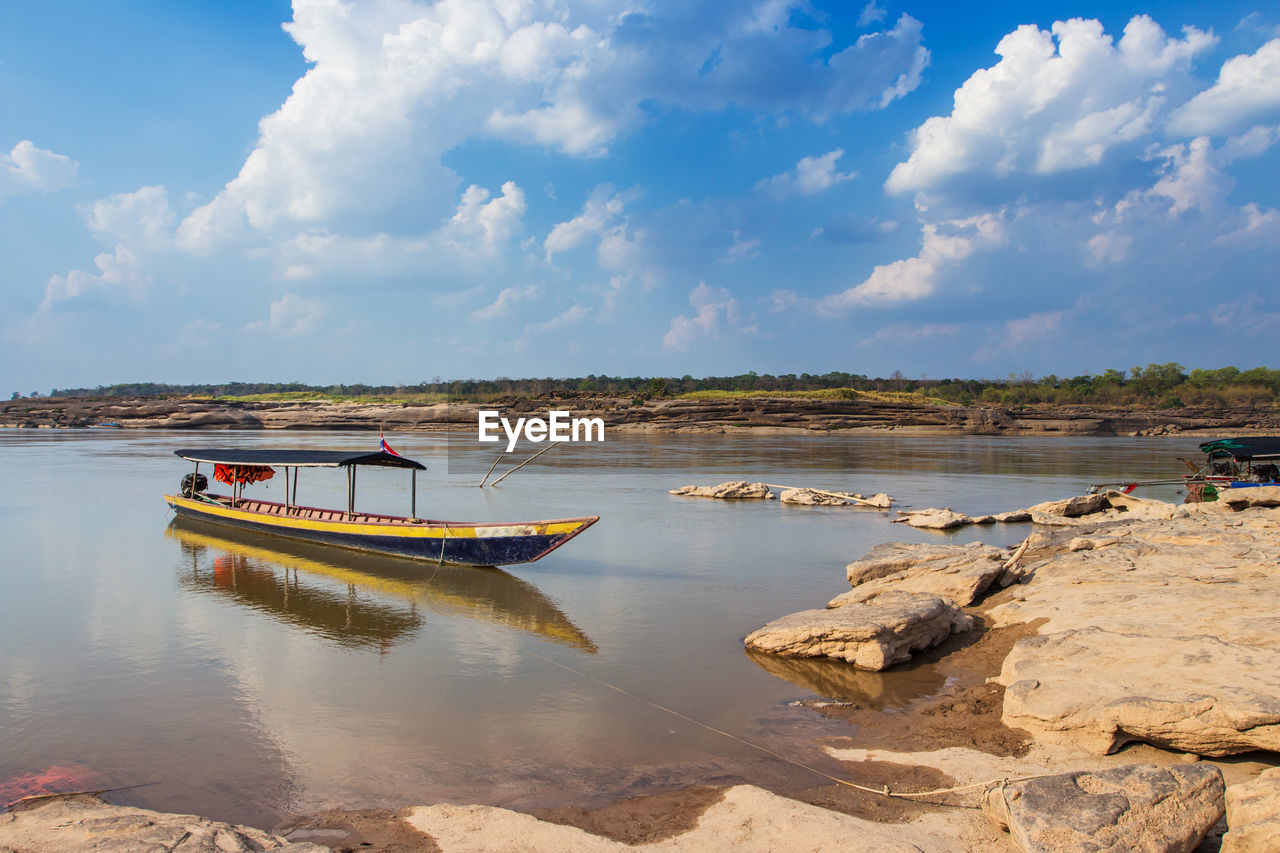 BOAT MOORED ON SHORE AGAINST SKY