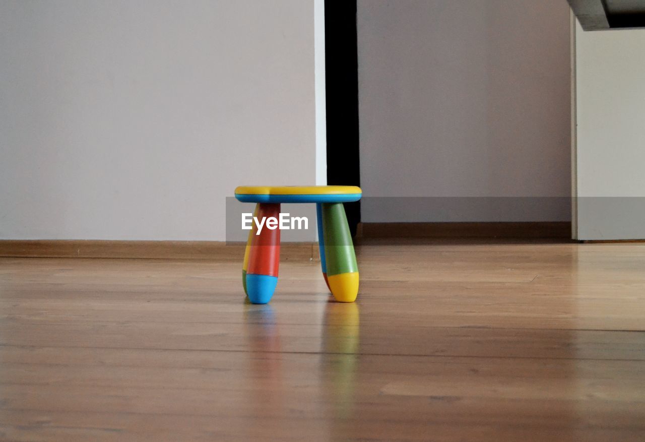 CLOSE-UP OF EMPTY CHAIR ON TABLE AGAINST WALL AT HOME