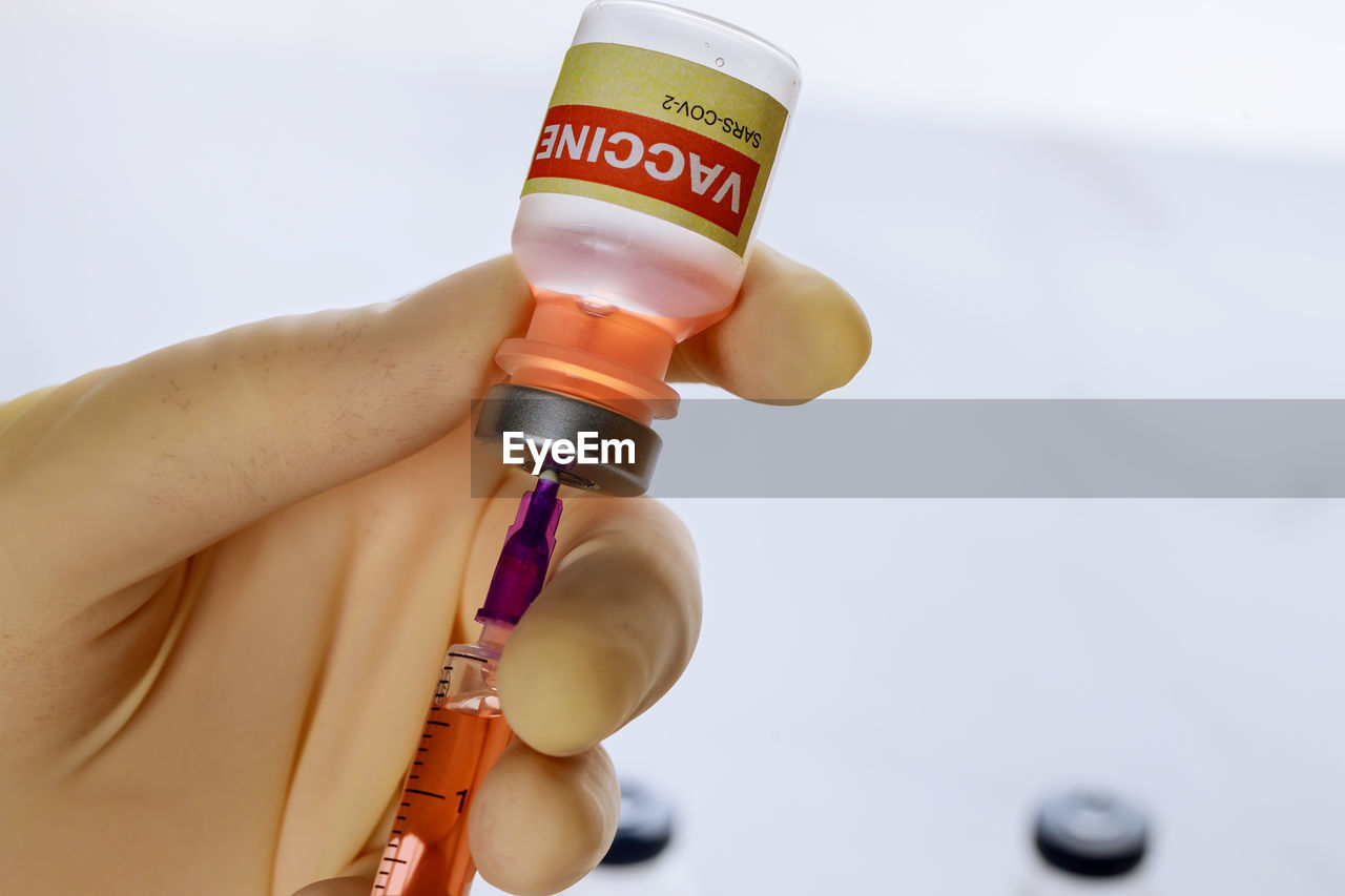 Close-up of hand holding coronavirus vaccine and syringe