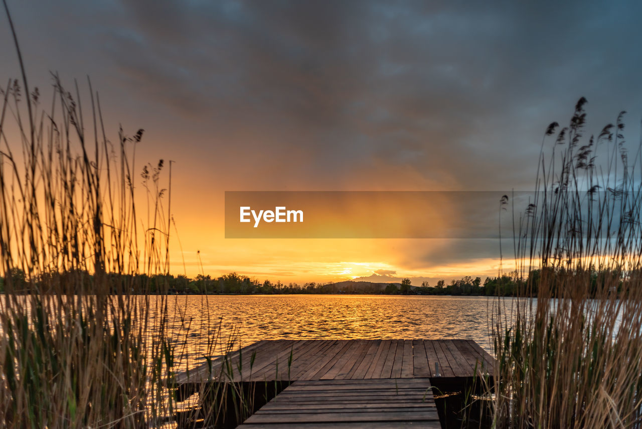 SCENIC VIEW OF LAKE AGAINST ORANGE SKY DURING SUNSET