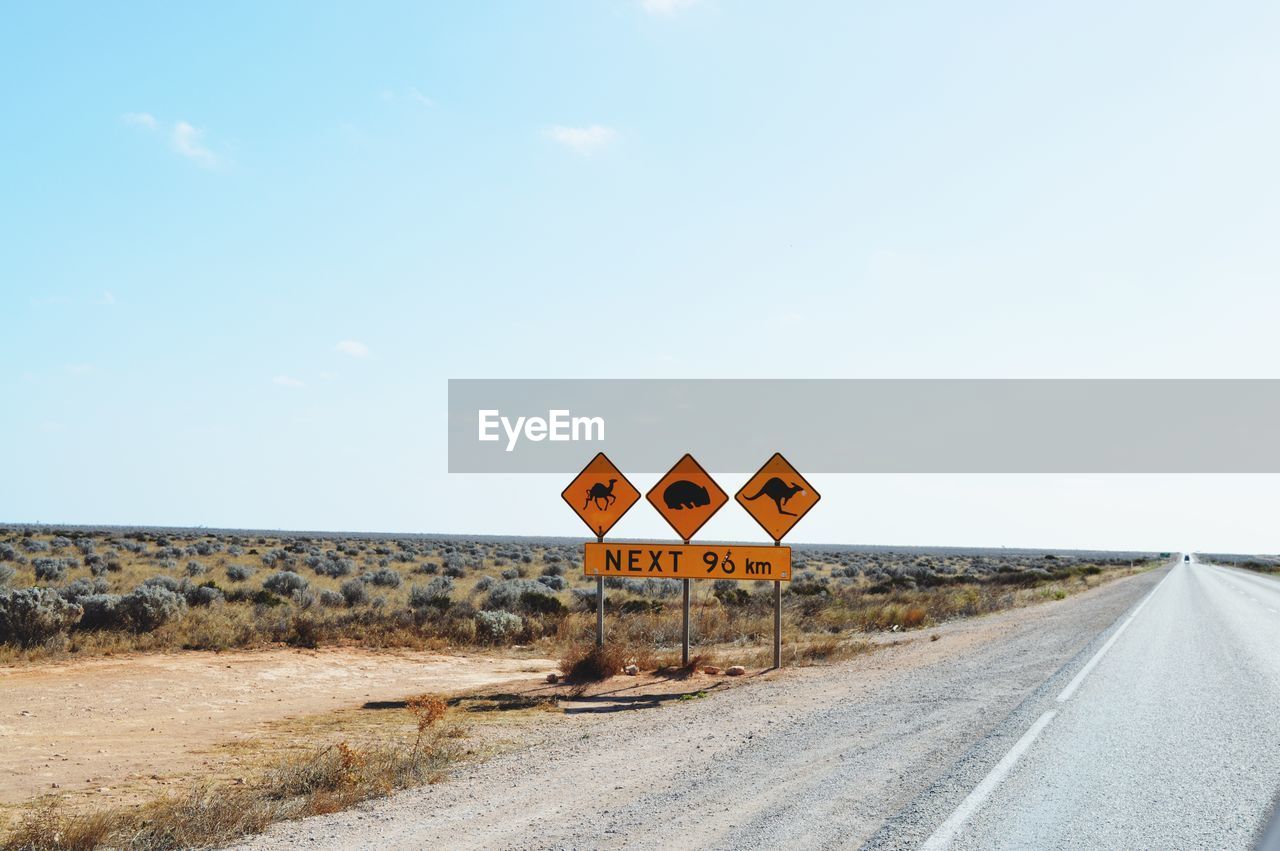 Animal crossing signs by road against sky