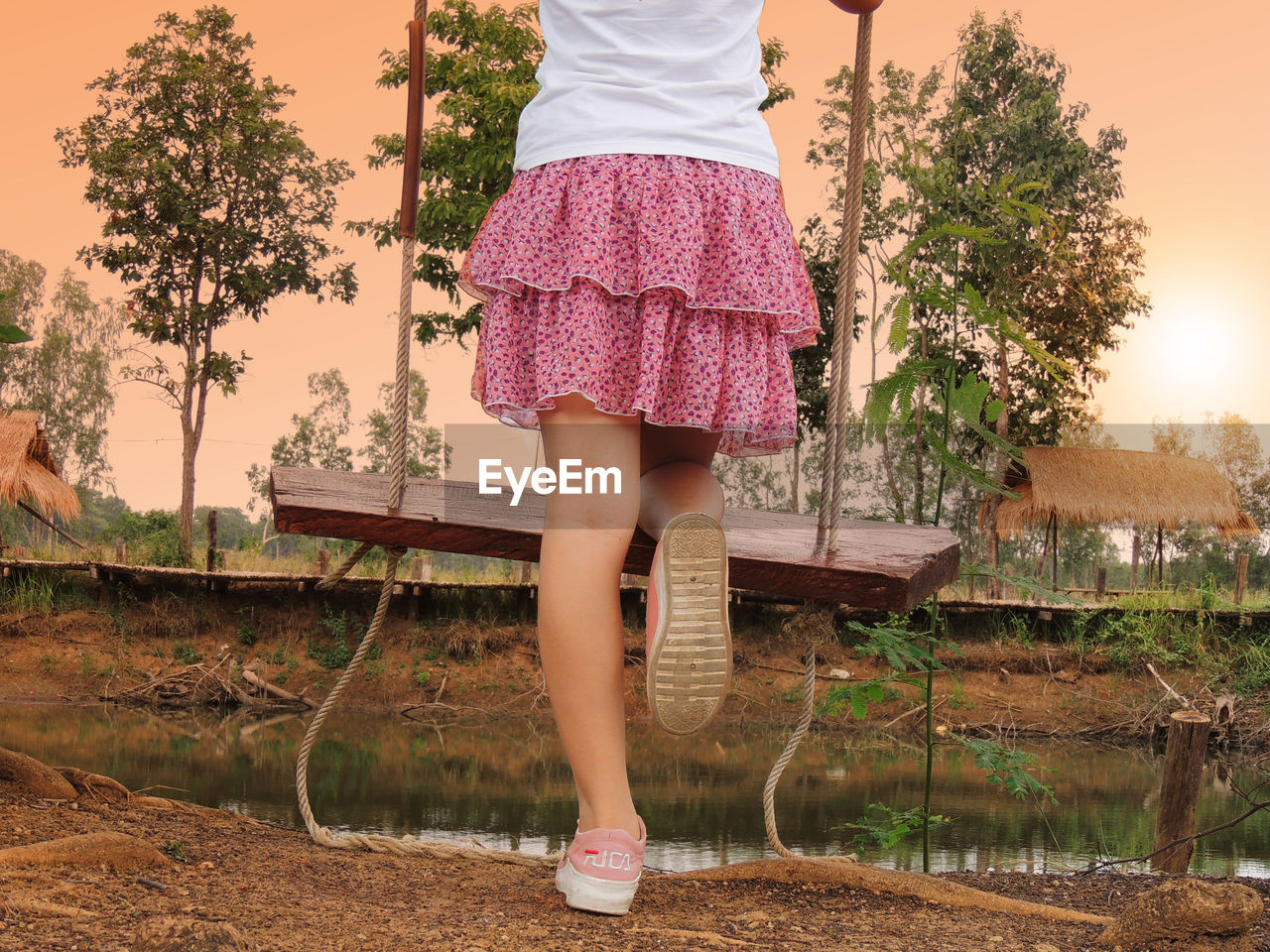 LOW SECTION OF WOMAN STANDING BY PLANTS AGAINST TREES