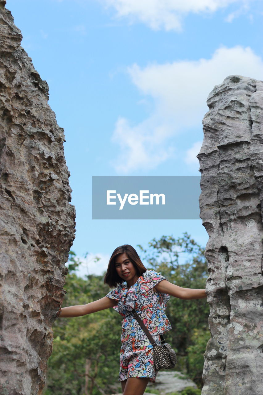 Portrait of young woman standing amidst rock formations