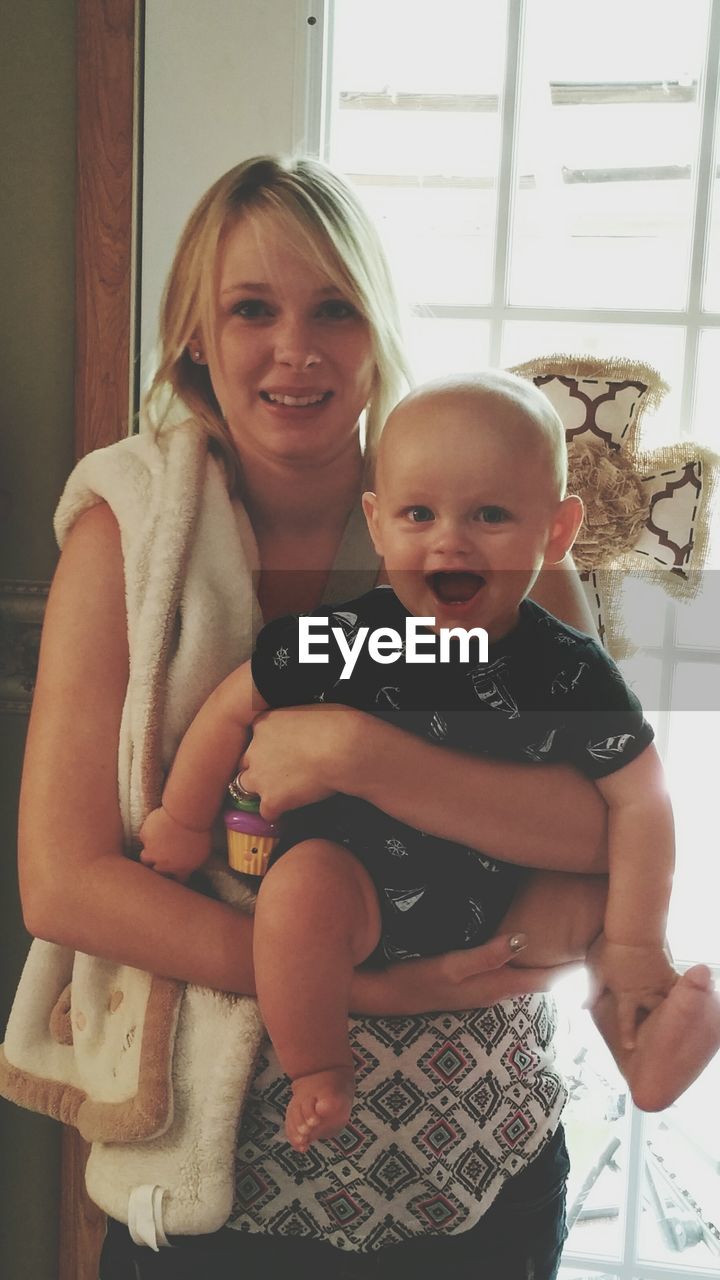 Portrait of smiling mother with son at home