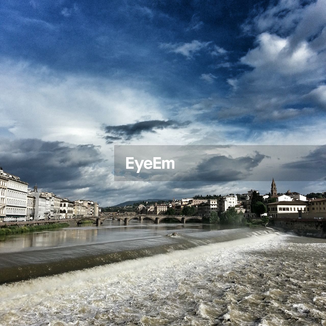 Bridge over water along buildings and against clouds