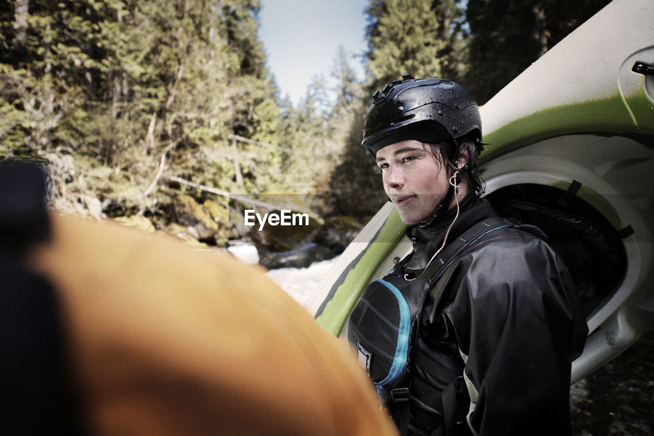 Kayaker looking at friend while standing in forest