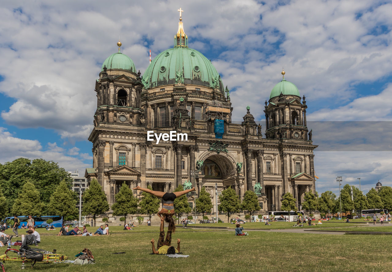 GROUP OF PEOPLE IN CATHEDRAL AGAINST CLOUDY SKY