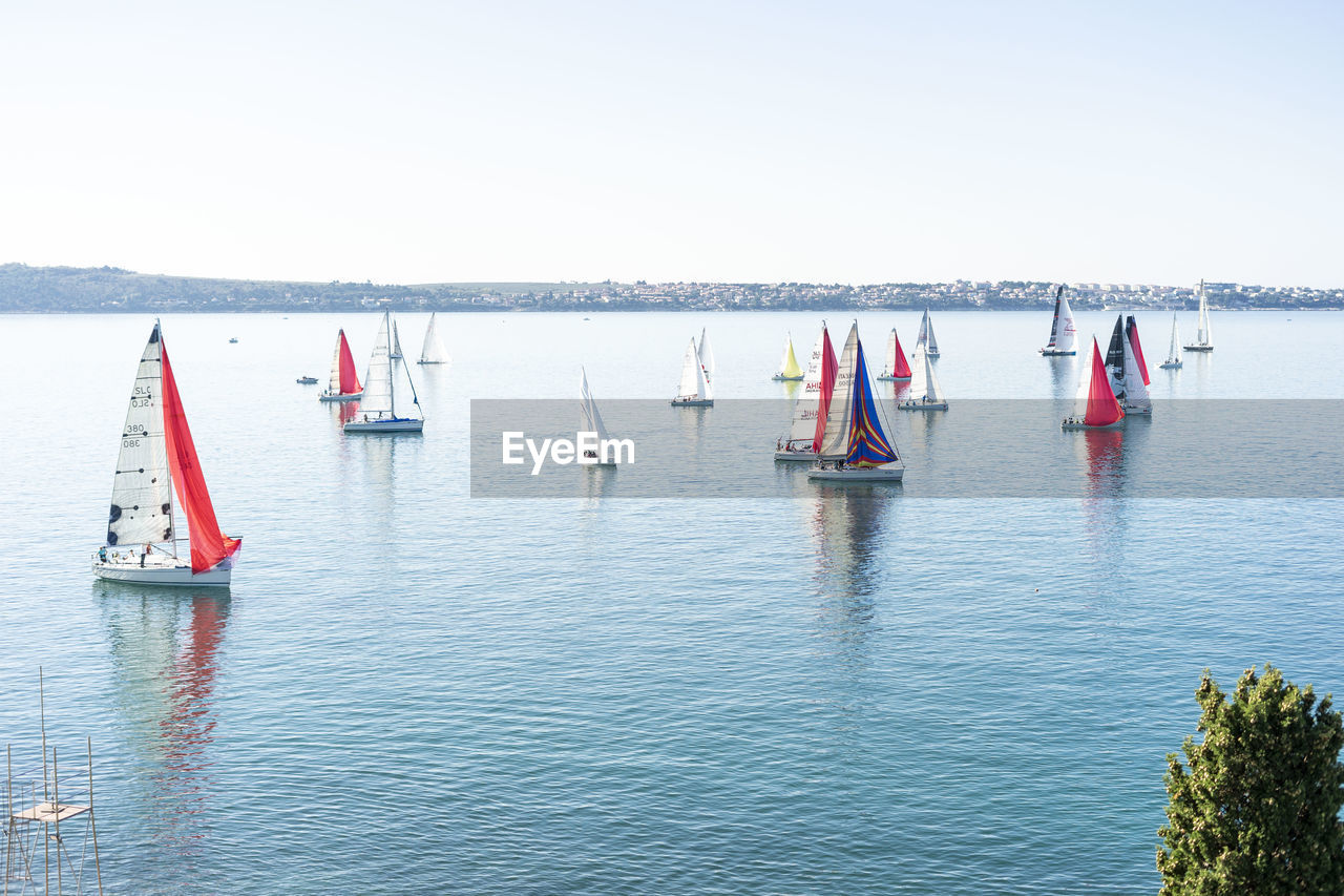 GROUP OF PEOPLE ON SAILBOAT IN SEA AGAINST CLEAR SKY