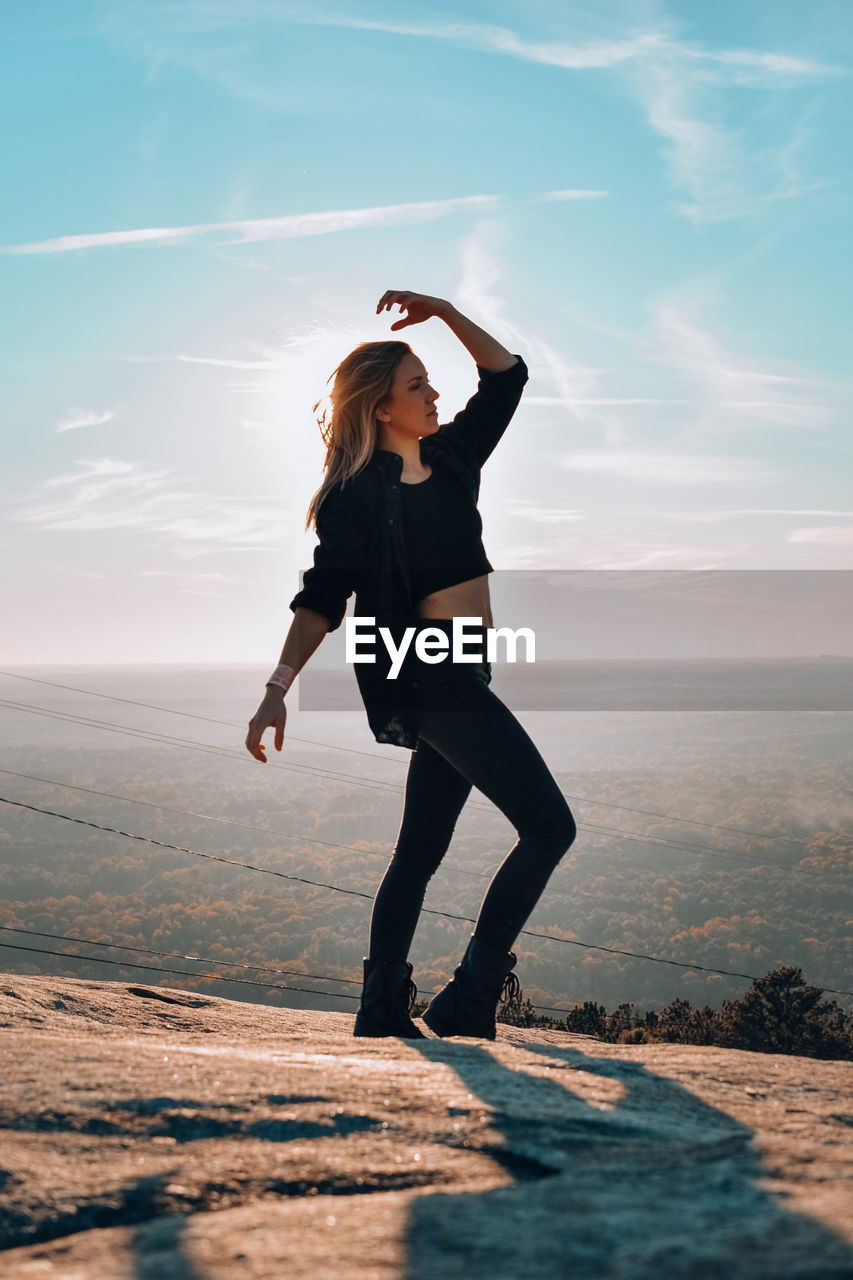 Full length of woman posing while standing on mountain against sky 