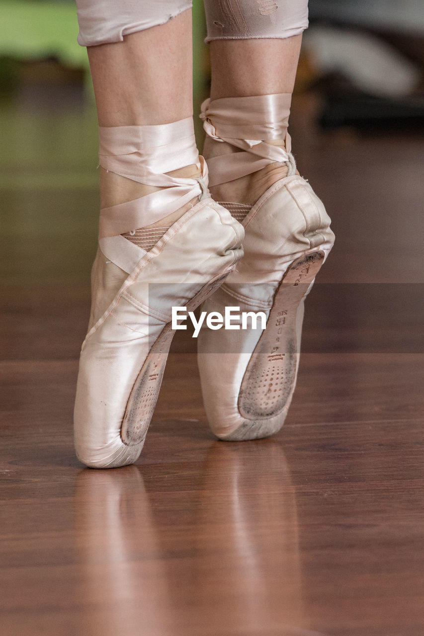 Low section of ballerina standing tiptoe on hardwood floor