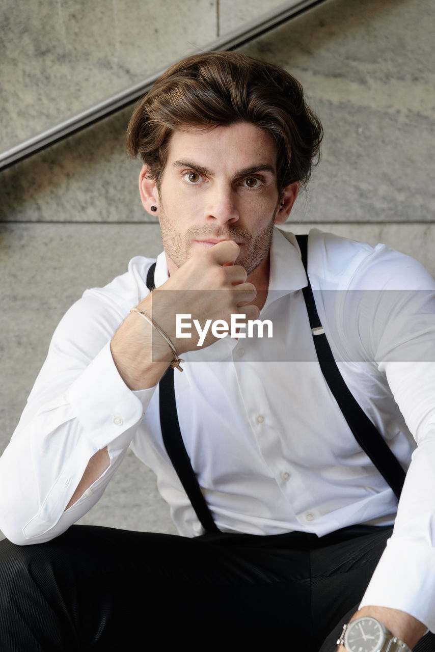 Portrait of man wearing suspenders while sitting on steps