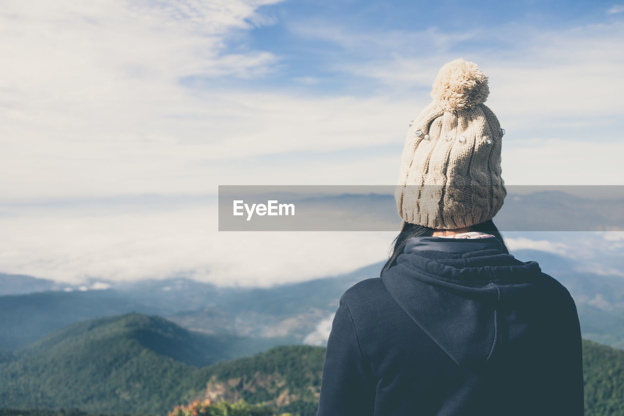 Rear view of woman standing on mountain against sky