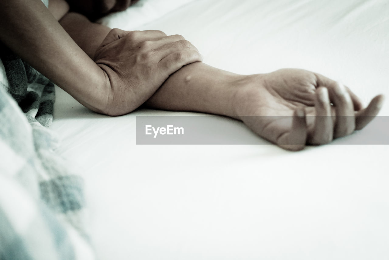 Cropped hands of man sleeping on bed