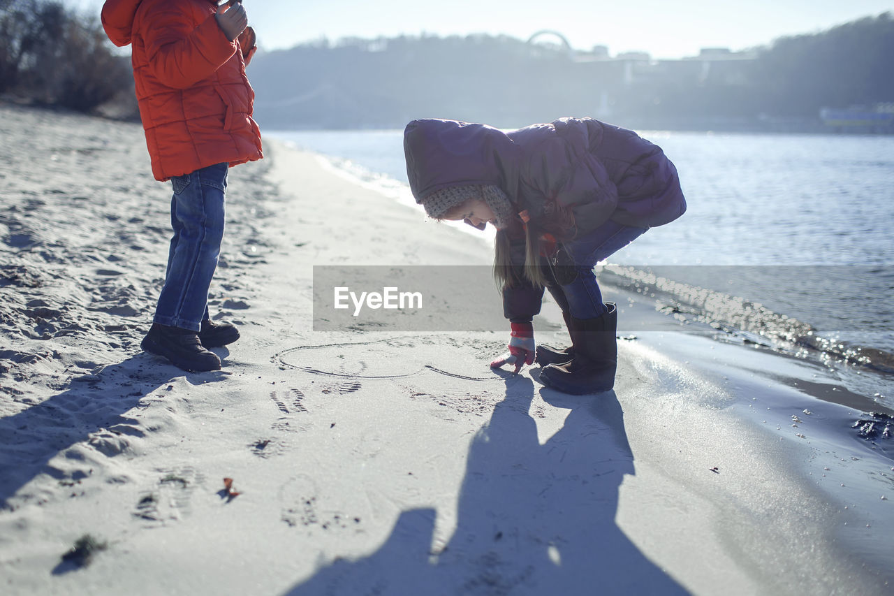 Full length of girl making heart shape on sand at beach