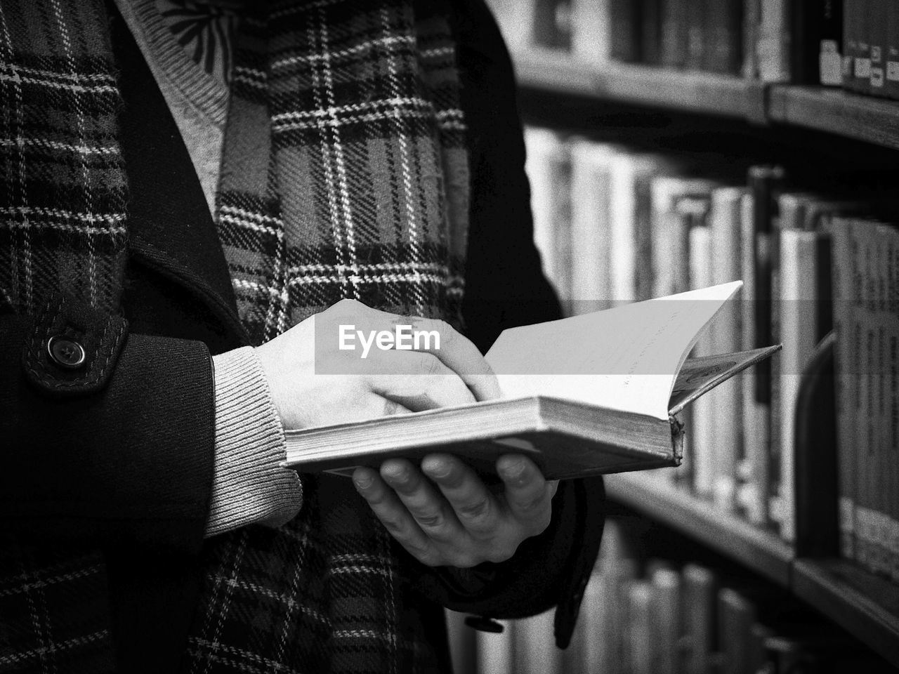 Midsection of man holding book in library